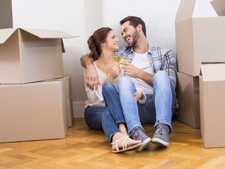 Cute couple toasting with champagne on floor