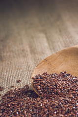 flax seeds with a wooden spoon on burlap background