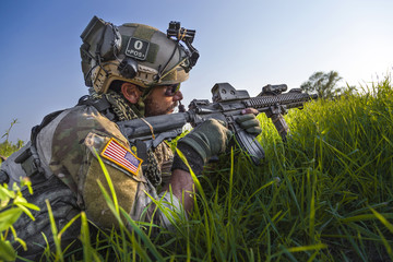 Wall Mural - American Soldier aiming his rifle on blue sky background