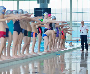 Wall Mural - group of happy kids children at swimming pool class learning to 