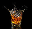 Glass of whiskey with splash on black background