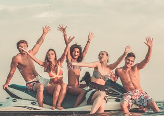  Group of happy multi ethnic friends sitting on a jet ski
