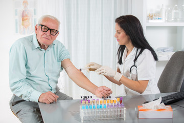 Nurse with syringe is taking blood for test at the doctor office