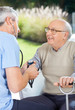 © Tyler Olson - Male Doctor Measuring Blood Pressure Of Elderly Man