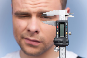 Man using vernier caliper on blue background.