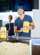 Happy Worker Holding Popcorn Paperbag At Concession Stand