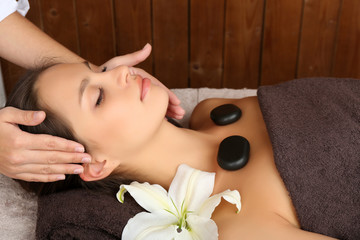 Beautiful young woman in spa salon with spa stones taking head