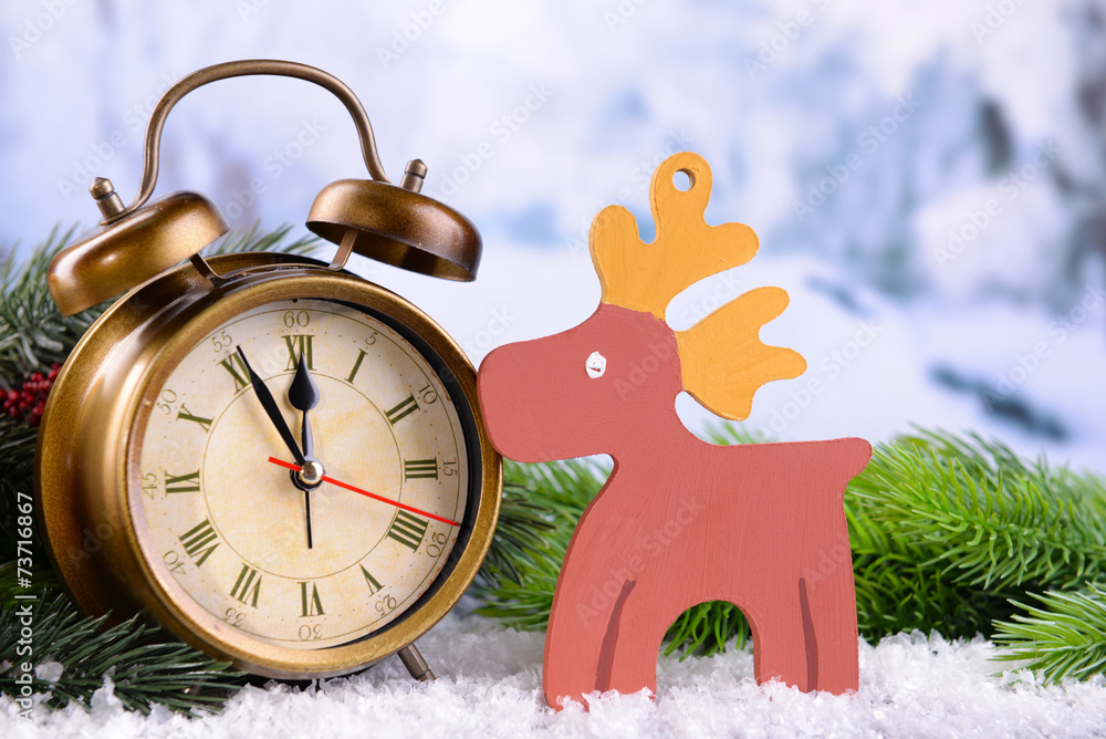 Alarm clock with Christmas decorations on light background