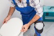 © WavebreakMediaMicro - Plumber installing lid on toilet