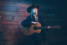 Cowgirl Country Singer With Acoustic Guitar. Wearing Blue Jeans