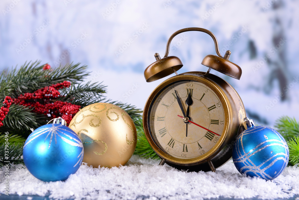 Alarm clock with Christmas decorations on light background