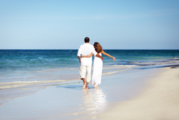 Loving couple walking on sandy beach.