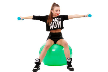 young sporty woman sitting on fitball with dumbbells on white ba