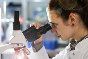 Wall Mural - scientist young woman using a microscope in a science laboratory