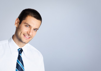 Wall Mural - Happy smiling young businessman, against grey