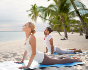 Canvas Print - happy couple making yoga exercises on beach