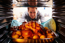 Man Taking Roast Turkey Out Of The Oven
