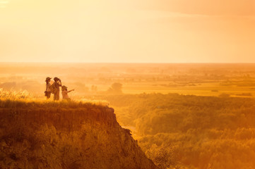 Children with tourists on a cliff at sunset