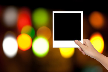 Canvas Print - Hand of Female Holding a Blank photo frame on colorful bokeh bac