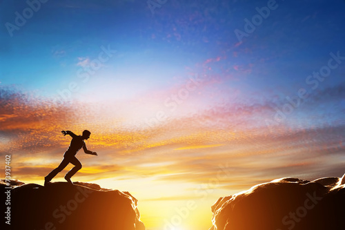 Fotografie, Obraz Man running fast to jump over precipice between two mountains