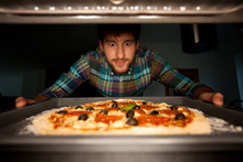Man Taking Pizza From Oven