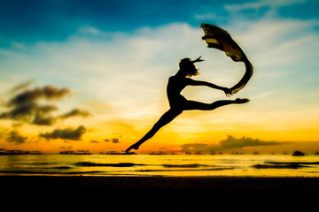 silhouette of jumping girl on tropical sunset sea and sky backgr