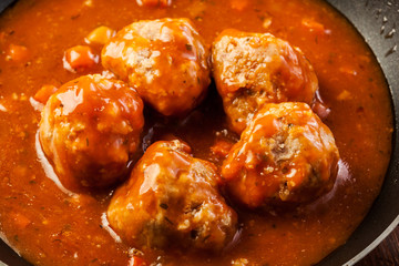 Meatballs with tomato sauce on black pan