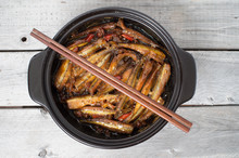 Vietnamese Caramelized Smelt Fishes In Clay Pot On A Wooden Tabl