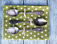 Metal Spoons On Green Polka Dot Napkin On Wooden Background