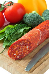 Wall Mural - Spanish chorizo sausage with vegetables on a wooden board