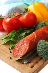 Wall Mural - Spanish chorizo sausage with vegetables on a wooden board