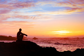 woman sitting alone at sunset near the sea