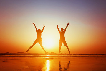 happy couple jumping on  the beach