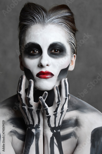 Fototapeta na wymiar Young woman with dead mask skull face art. Halloween face