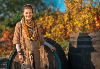 Wall Mural - Portrait of happy young woman standing near wooden barrel 