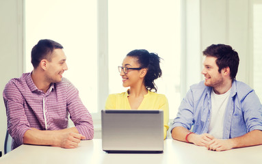 Canvas Print - three smiling colleagues with laptop in office