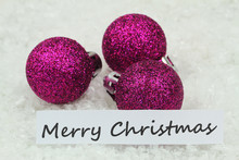 Merry Christmas Card With Purple Baubles On Snowy Surface