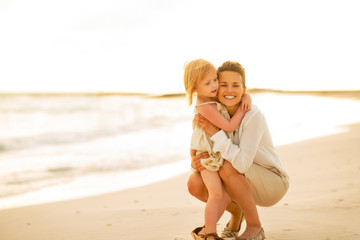 Wall Mural - Portrait of happy mother and baby girl on beach at the evening