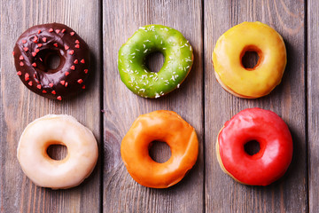 Sticker - Delicious donuts with glaze on wooden background