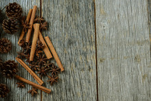 Cinnamon Sticks, Star Anise And Pine Cones On Rustic Wood Backgr