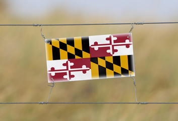 Wall Mural - Border fence - Old plastic sign with a flag