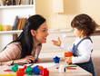 © BalanceFormCreative - Mother and baby girl playing with toys in living room.