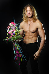 Wall Mural -  male fitness model shirtless holding a bouquet of flowers. 