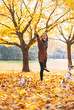 © Alliance - Happy young woman playing with dogs outdoors in autumn