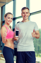 Sticker - smiling young woman with personal trainer in gym