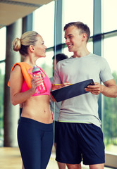 Wall Mural - smiling young woman with personal trainer in gym