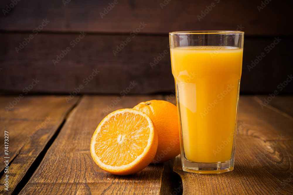 Orange fruit and glass of juice on brown wooden background - obrazy, fototapety, plakaty 