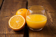 Orange fruit and glass of juice on dark wooden table