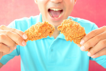 A man with opening mouth about to eat deep fried chicken legs or