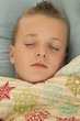 Cute young boy asleep under a snowflake blanket peace